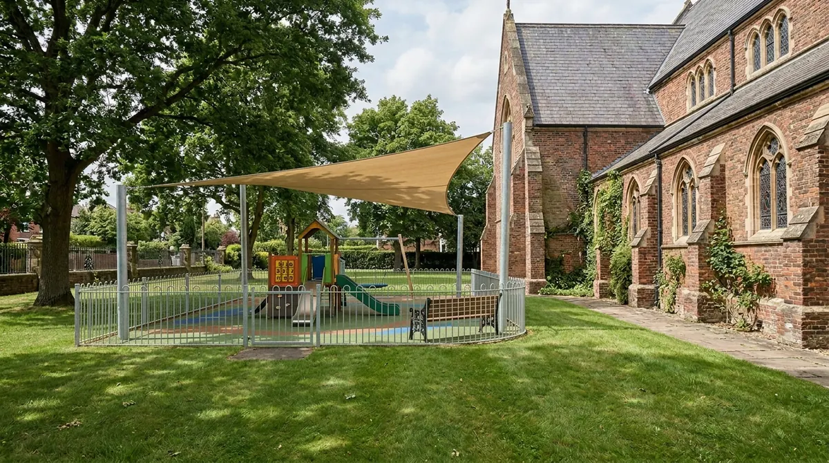 After: a Fenced Play Area | Music City Playgrounds After: The same lawn with a fenced play area, a small commercial play structure, soft rubber surfacing, a shade sail and a bench, bright daylight