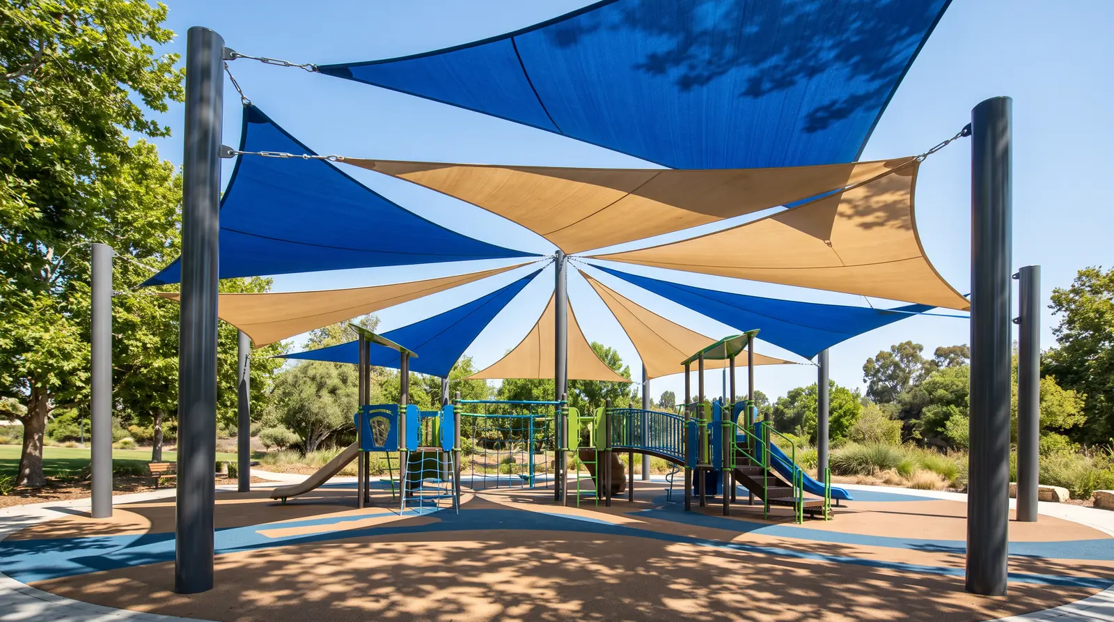 Shade Sail Over a Play Structure | Music City Playgrounds Large triangular shade sails in blue and sand over a commercial play structure, steel posts, soft dappled shade on the surfacing, bright sunny day